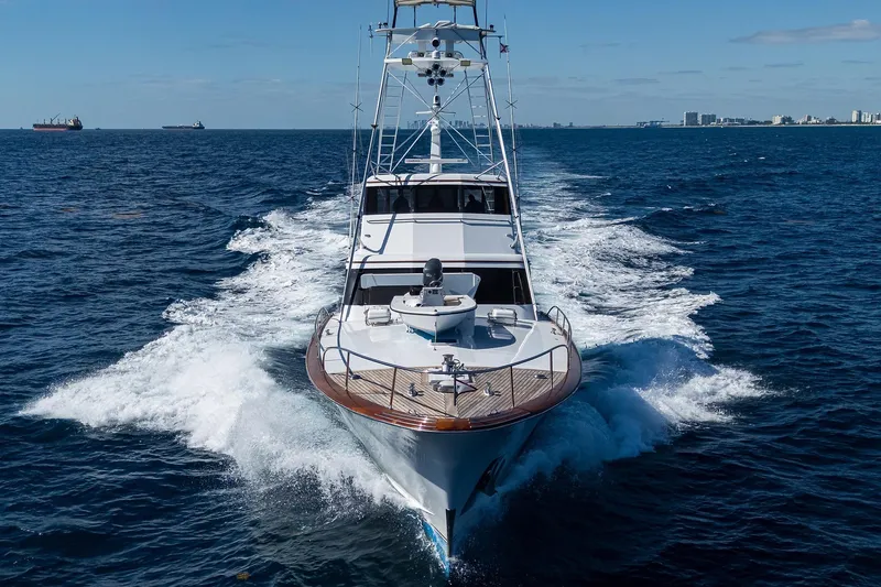 Slide: The Image of Feadship 1985 Yacht Fisherman cruising on open sea, clear skies, city skyline in background. - 144
