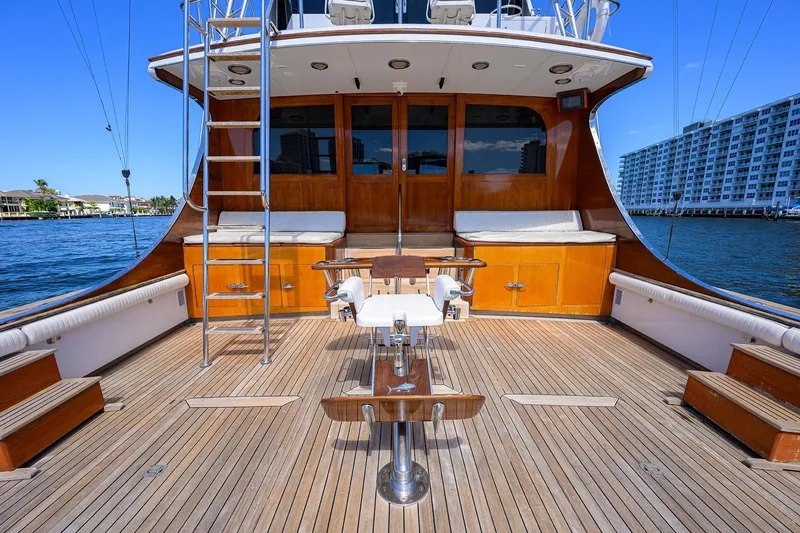Slide: The Image of 1985 Feadship Yacht Fisherman deck with wooden flooring and fishing chair, docked by waterfront. - 16