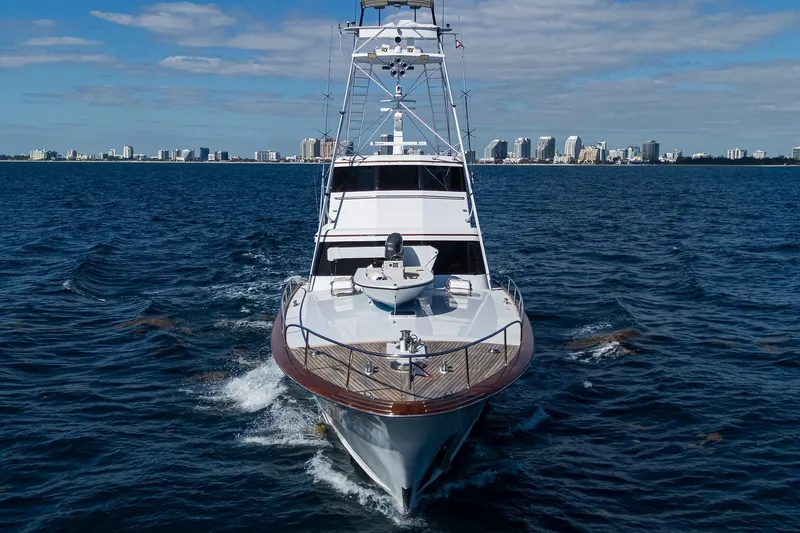 Slide: The Image of 1985 Feadship Yacht Fisherman cruising on open water with city skyline backdrop. - 4