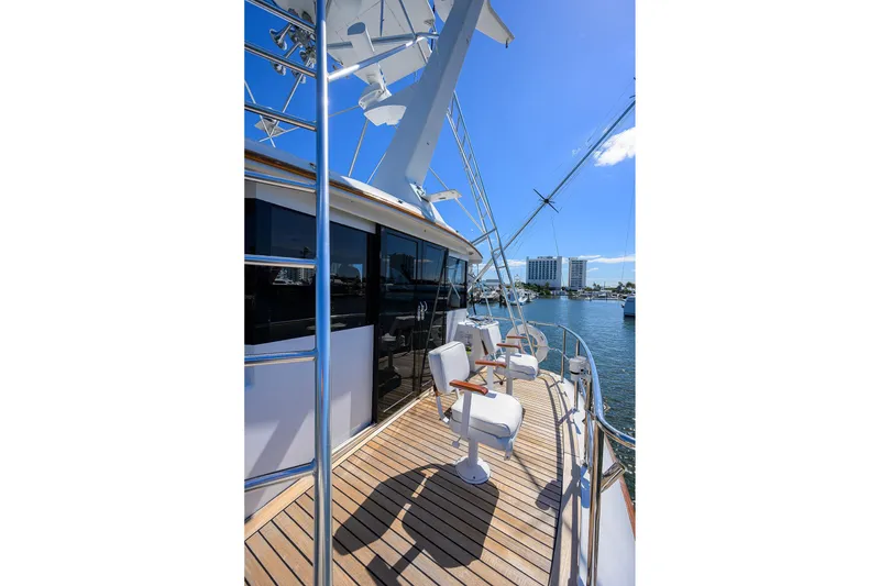 Slide: The Image of 1985 Feadship Yacht Fisherman deck with chairs, overlooking marina under clear blue sky. - 49
