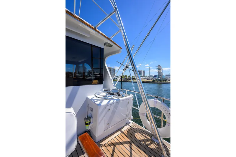Slide: The Image of 1985 Feadship Yacht Fisherman deck with steering wheel, overlooking marina and cityscape. - 52