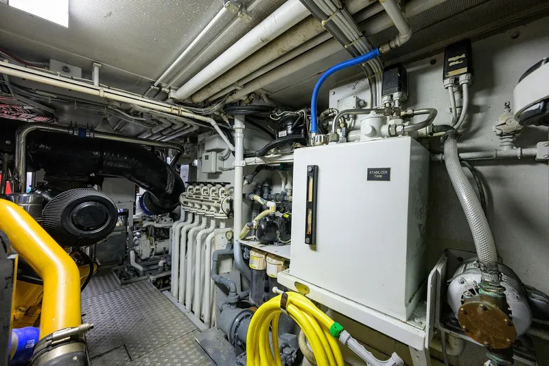 Slide: The Image of Engine room of a 1985 Feadship Yacht Fisherman, showcasing complex machinery and piping. - 76