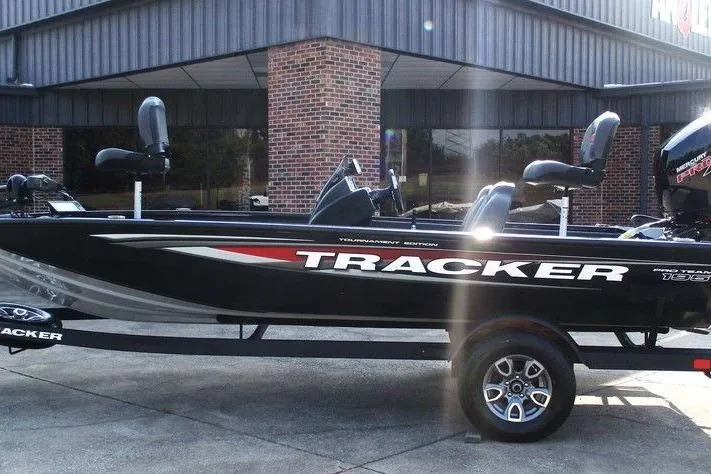 The Image of 2026 Tracker Pro Team 195 Tournament Edition boat, black with red accents, parked outside a building. - 1