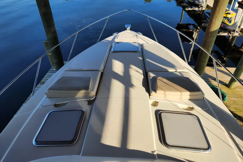Slide: The Image of 2015 Formula 34 Performance Cruiser deck with sun pads and hatches, docked by calm water. - 59