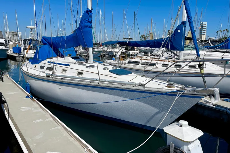 Slide: The Image of 1984 Hunter 34 sailboat docked in marina with blue covers and clear sky. - 1