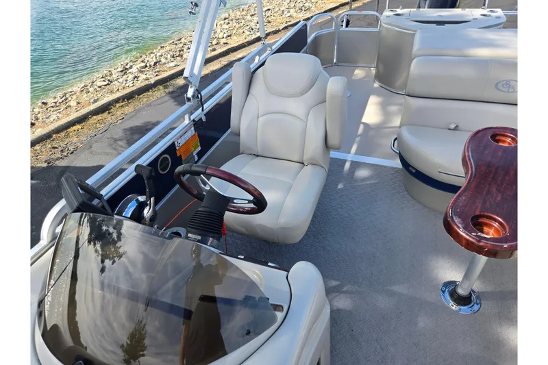 Slide: The Image of 2014 South Bay 522 FCR boat interior with steering wheel, seating, and table by the water. - 11