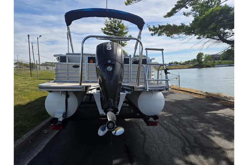 Slide: The Image of 2014 South Bay 522 FCR pontoon boat with outboard motor, parked near a scenic lake. - 2