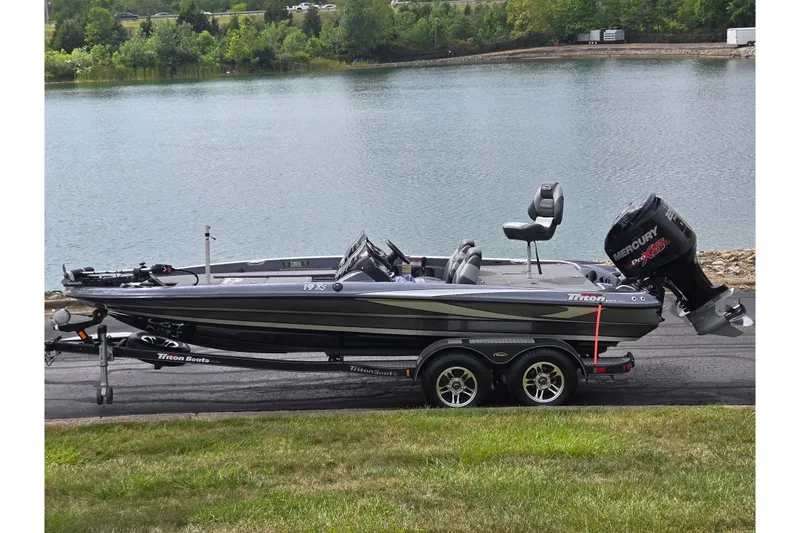 Slide: The Image of 2014 Triton 19XS boat on trailer by a lake, featuring a Mercury Pro XS engine. - 0