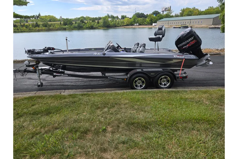 Slide: The Image of 2014 Triton 19XS boat on trailer by a lake, featuring a Mercury engine. - 11