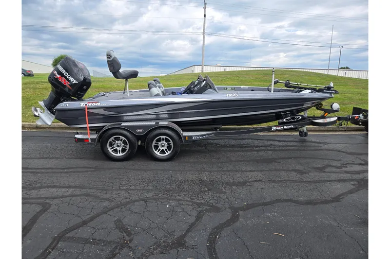 Slide: The Image of 2014 Triton 19XS boat on trailer, parked outdoors, featuring dual axles and Mercury engine. - 4