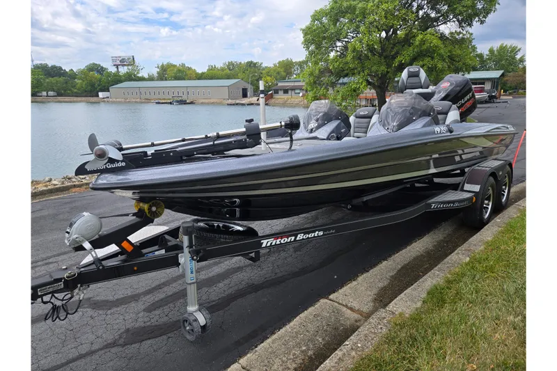 Slide: The Image of 2014 Triton 19XS bass boat on trailer by a lakeside, ready for fishing adventures. - 8