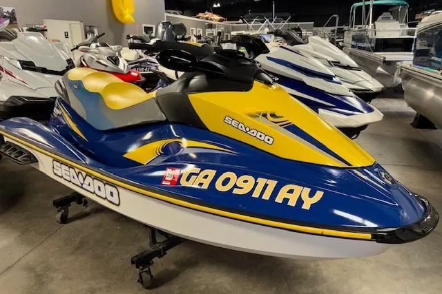 Slide: The Image of 2006 Sea-Doo GTI SE jet ski in showroom, blue and yellow design, side view. - 1