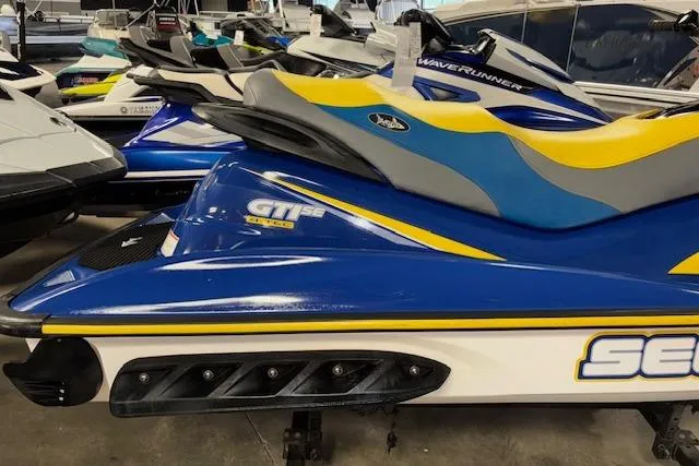 Slide: The Image of 2006 Sea-Doo GTI SE jet ski in blue and yellow, parked indoors. - 5