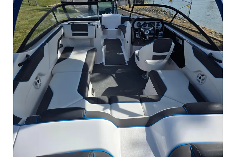 Slide: The Image of 2020 Yamaha Boats AR210 interior with modern seating and steering, docked by the water. - 11