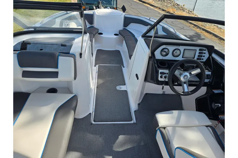 Slide: The Image of 2020 Yamaha Boats AR210 interior with modern dashboard and seating, docked by the water. - 12