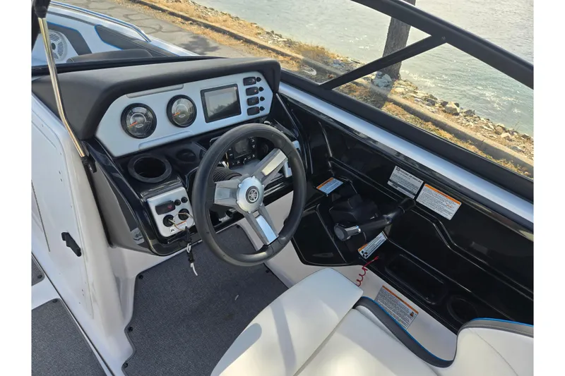 Slide: The Image of 2020 Yamaha AR210 boat cockpit with steering wheel, gauges, and controls by the water. - 15
