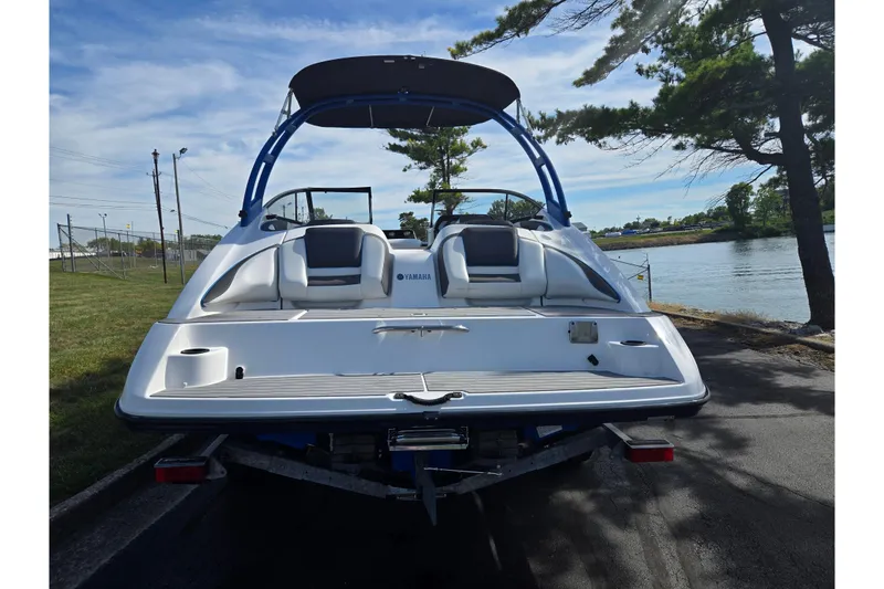 Slide: The Image of 2020 Yamaha Boats AR210 on trailer by lakeside, rear view. - 2