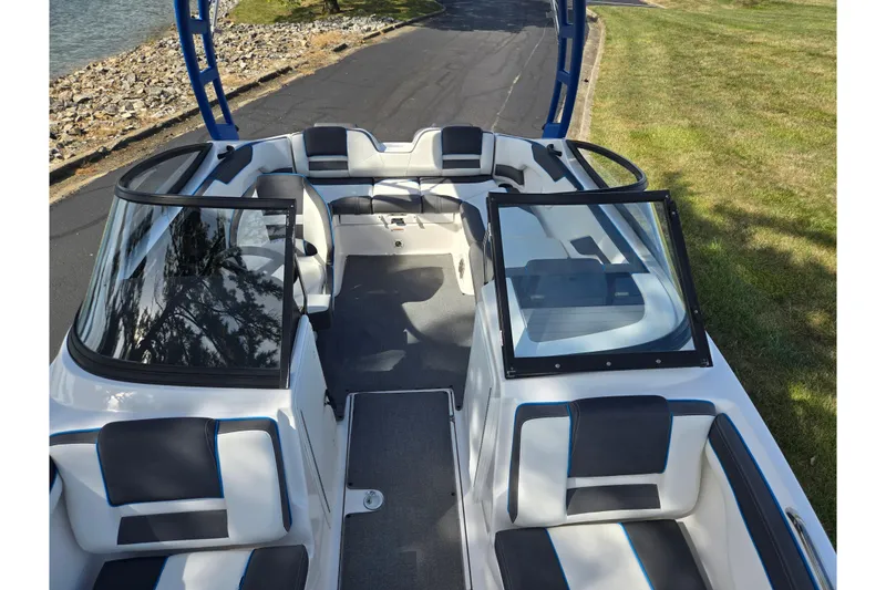 Slide: The Image of 2020 Yamaha Boats AR210 interior with seating, windshield, and sleek design near water. - 23