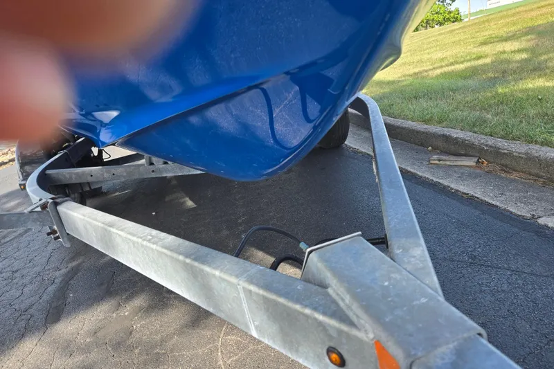Slide: The Image of 2020 Yamaha Boats AR210 on trailer, blue hull, parked on asphalt near grass. - 6