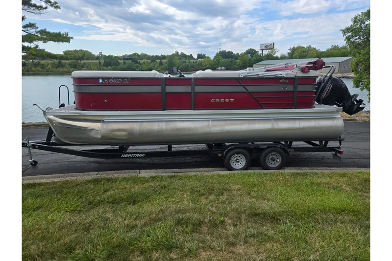 Slide: The Image of 2022 Crest Classic LX 220 pontoon boat on trailer by a lake. - 10