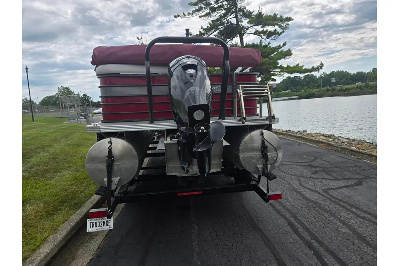 Slide: The Image of 2022 Crest Classic LX 220 pontoon boat on trailer by a lakeside road. - 2