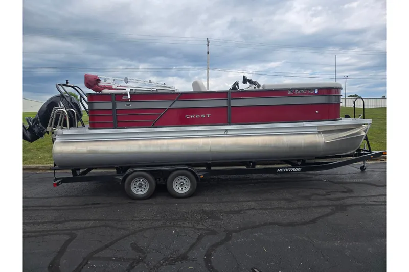 Slide: The Image of 2022 Crest Classic LX 220 pontoon boat on trailer, parked outdoors under cloudy sky. - 4