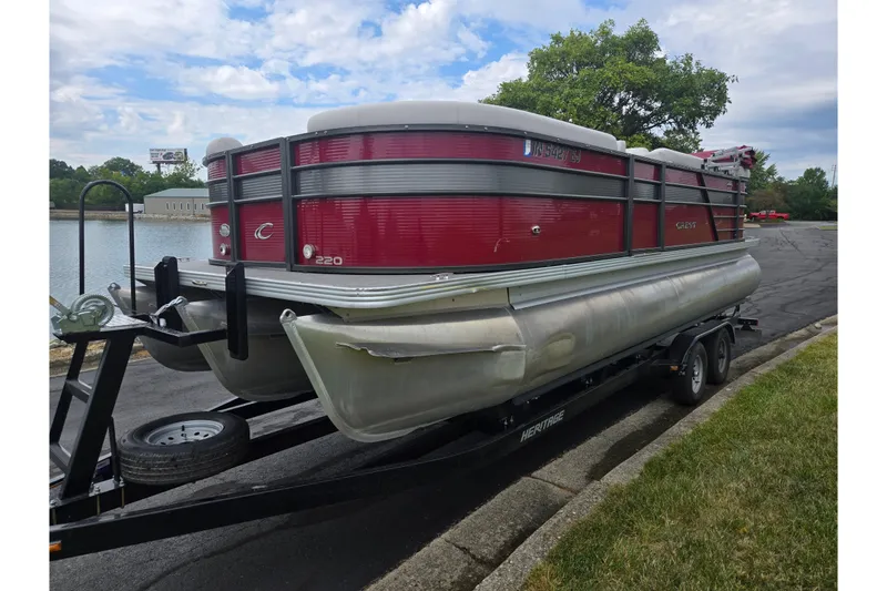 Slide: The Image of 2022 Crest Classic LX 220 pontoon boat on trailer by a lake. - 8