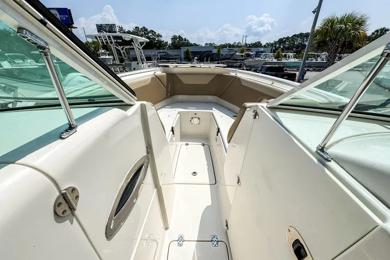 Slide: The Image of 2018 Sailfish 275 DC boat interior with seating and storage, under a sunny sky. - 12
