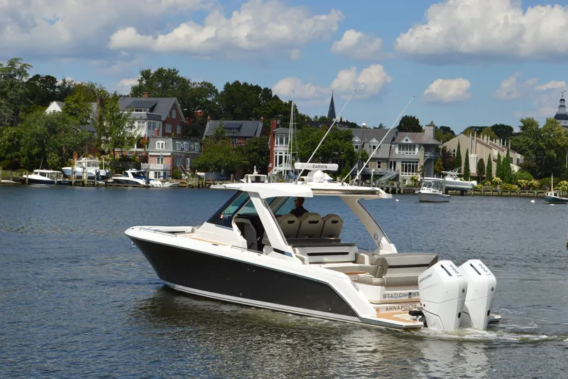 Slide: The Image of 2024 Tiara Yachts 34 LS cruising on a scenic waterfront with luxury homes. - 2