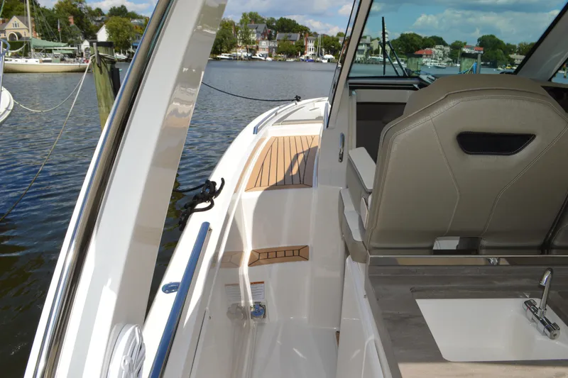 Slide: The Image of 2024 Tiara Yachts 34 LS interior with seating and sink, docked by a scenic waterfront. - 22