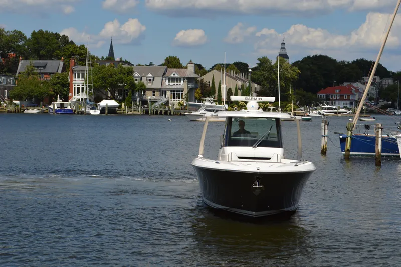 Slide: The Image of 2024 Tiara Yachts 34 LS cruising on a scenic waterfront with houses and boats. - 3