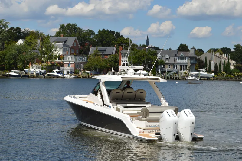 Slide: The Image of 2024 Tiara Yachts 34 LS cruising on a scenic waterfront with houses in the background. - 4