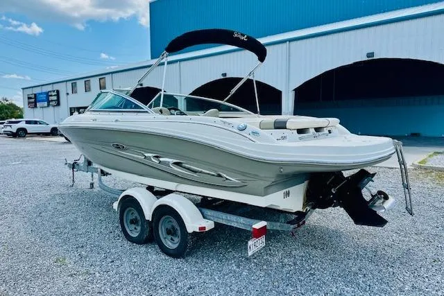 Slide: The Image of 2005 Sea Ray 200 Select boat on trailer, parked outdoors near a blue building. - 2