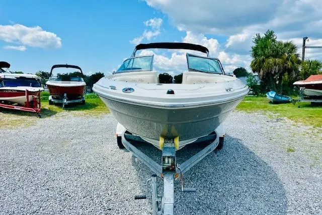 Slide: The Image of 2005 Sea Ray 200 Select boat on trailer, parked outdoors near a blue building. - 5