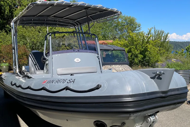 Slide: The Image of 2013 Sealegs 7.7 RIB boat with canopy, parked outdoors on a sunny day. - 2