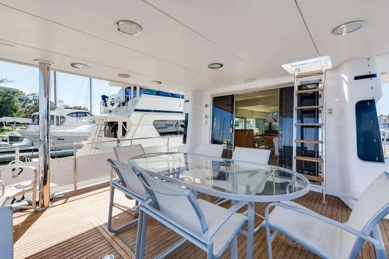 Slide: The Image of 1988 Azimut Motor Yacht deck with glass table, chairs, and ladder, docked at marina. - 19