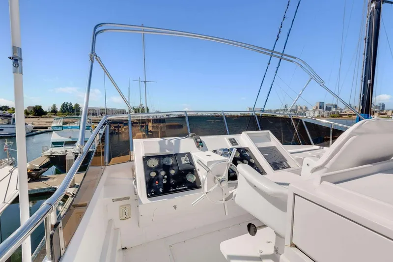 Slide: The Image of 1988 Azimut Motor Yacht helm with marina view, featuring control panel and steering wheel. - 24