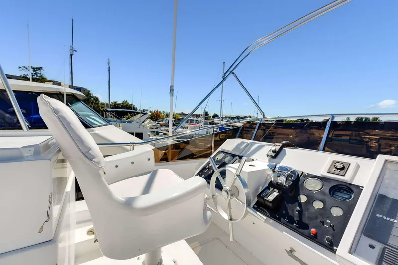 Slide: The Image of 1988 Azimut Motor Yacht helm with steering wheel and control panel, docked under clear blue sky. - 25