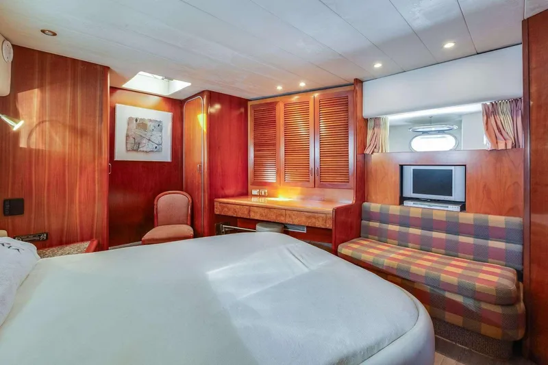 Slide: The Image of Luxurious 1988 Azimut Motor Yacht cabin with wood paneling, bed, seating, and TV. - 32
