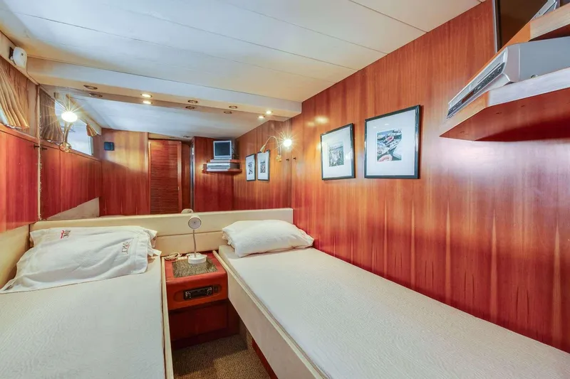 Slide: The Image of 1988 Azimut Motor Yacht cabin with twin beds, wooden paneling, and framed artwork. - 35