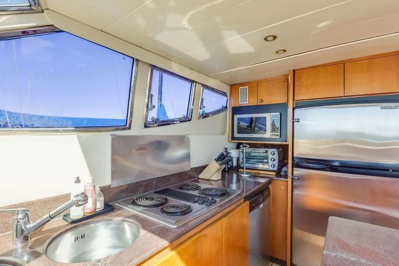 Slide: The Image of 1988 Azimut Motor Yacht kitchen with stove, sink, microwave, and stainless steel fridge. - 8