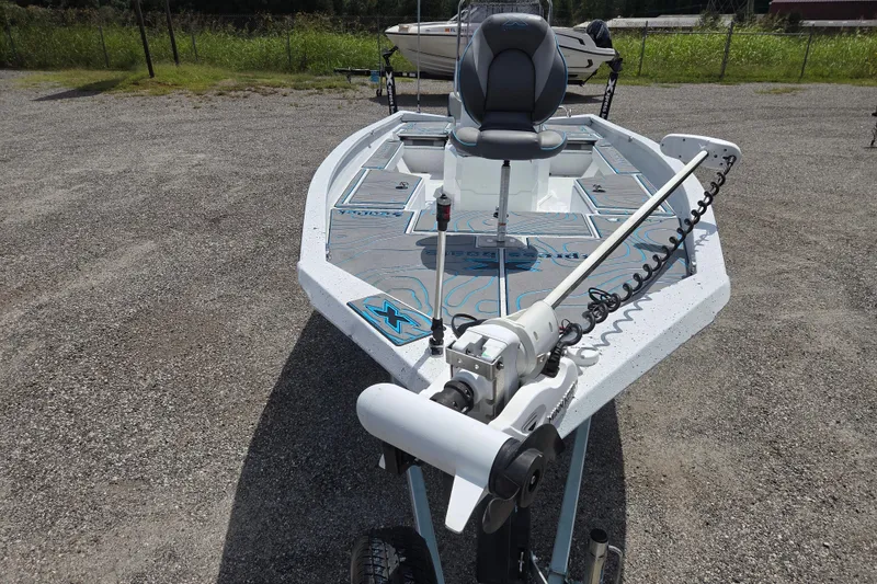Slide: The Image of 2022 Xpress H22B boat with advanced trolling motor and seating, parked on gravel. - 2