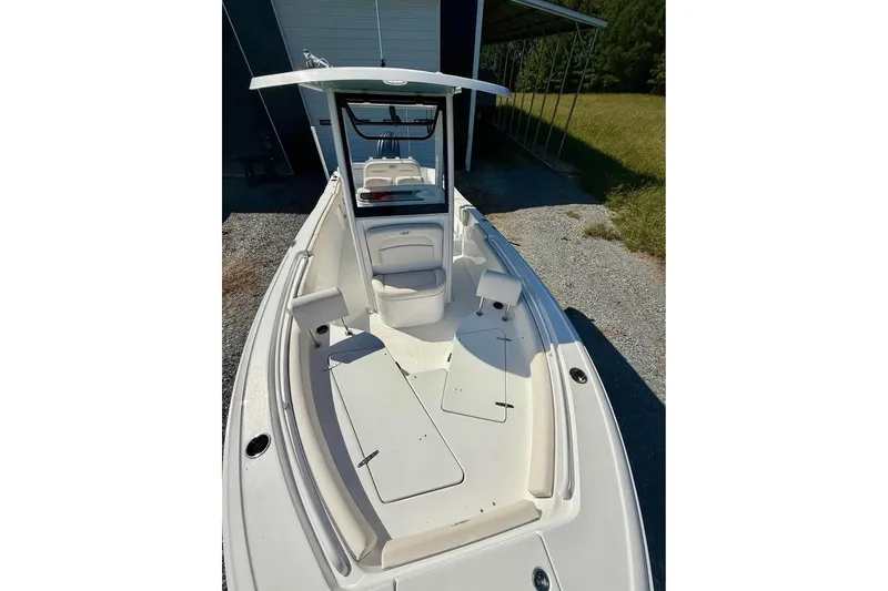 Slide: The Image of 2026 Sea Hunt Ultra 235 SE boat with spacious deck and seating, parked outdoors. - 10