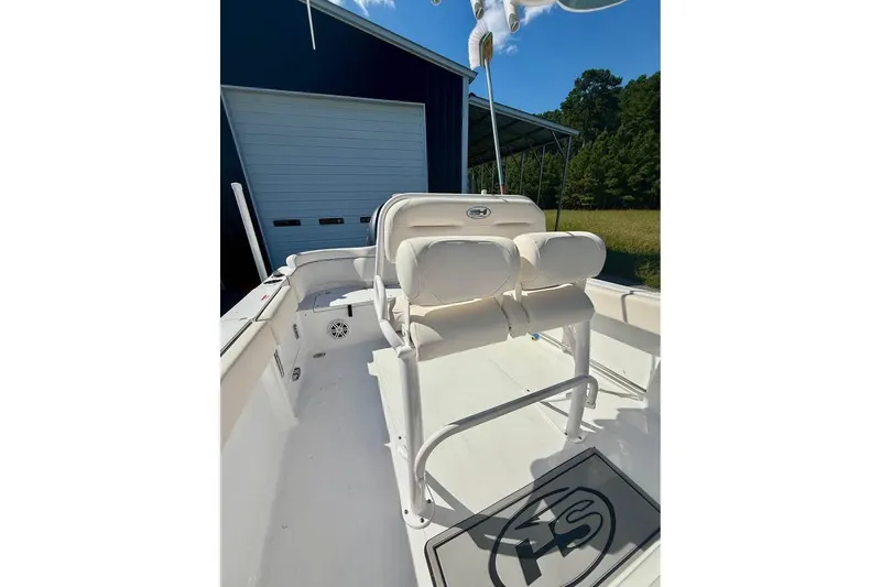 Slide: The Image of 2026 Sea Hunt Ultra 235 SE boat interior with seating and storage, parked near a garage. - 7