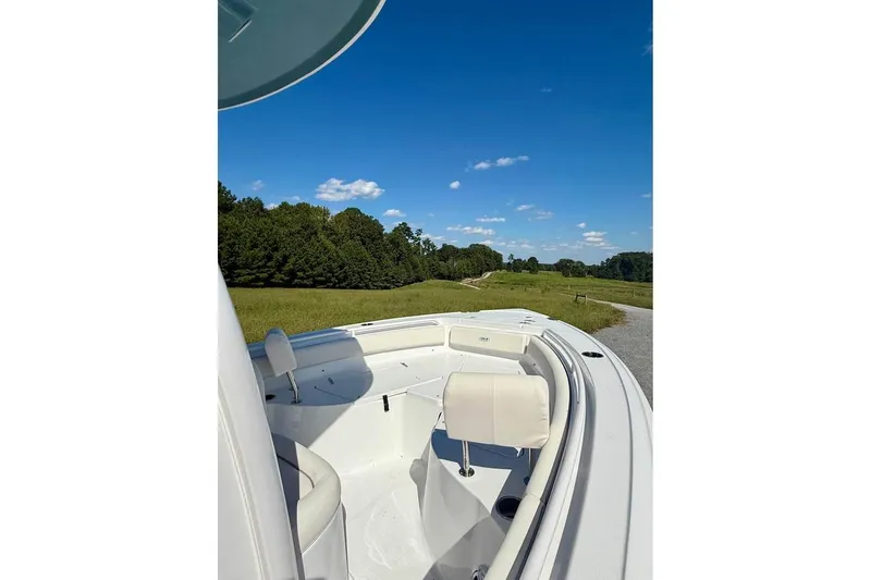 Slide: The Image of 2026 Sea Hunt Ultra 235 SE boat on a scenic grassy landscape under a clear blue sky. - 9