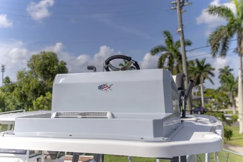 Slide: The Image of 2024 Crevalle 26 HCO boat console with steering wheel, outdoors with palm trees. - 14