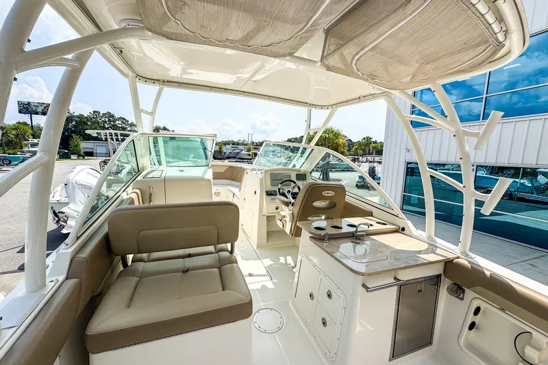 Slide: The Image of 2018 Sailfish 275 DC boat interior with seating, helm, and kitchenette under a canopy. - 4