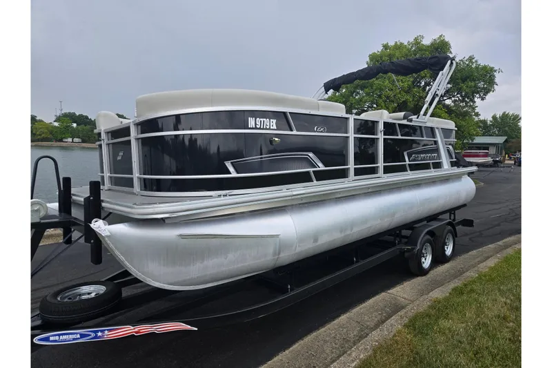 Slide: The Image of 2023 Starcraft EX 22 R pontoon boat on trailer, parked near a lake. - 7