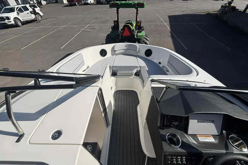 Slide: The Image of 2026 Bayliner VR6 Bowrider I/O boat interior with seating and dashboard in a parking lot. - 2