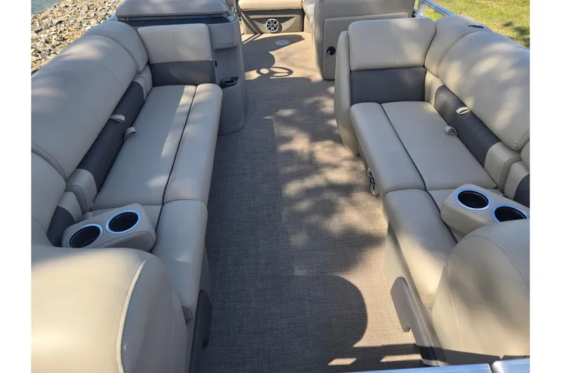 Slide: The Image of 2024 Sun Tracker Party Barge 20 DLX interior with beige seating and cup holders. - 10